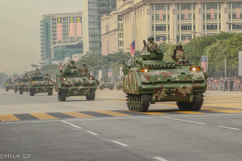 Armoured vehicles moving along a city parade route