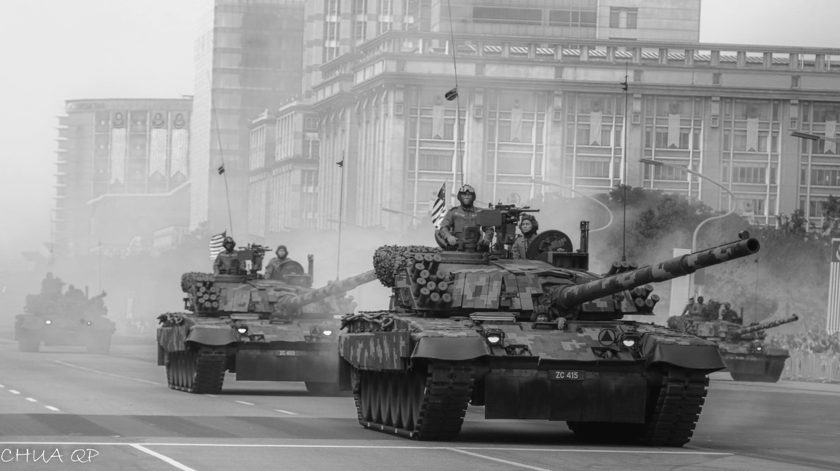 Black-and-white photograph of tanks on a city parade route