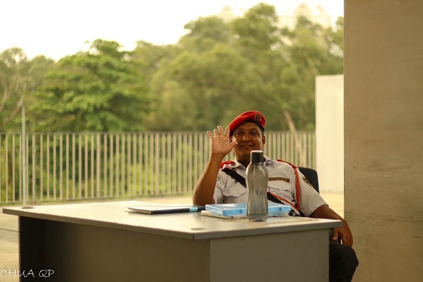 Smiling person in a red beret seated at a table beside greenery