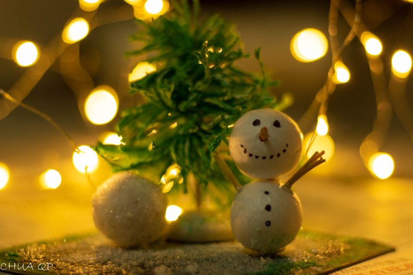 Snowman decorations beside a small Christmas tree and warm lights