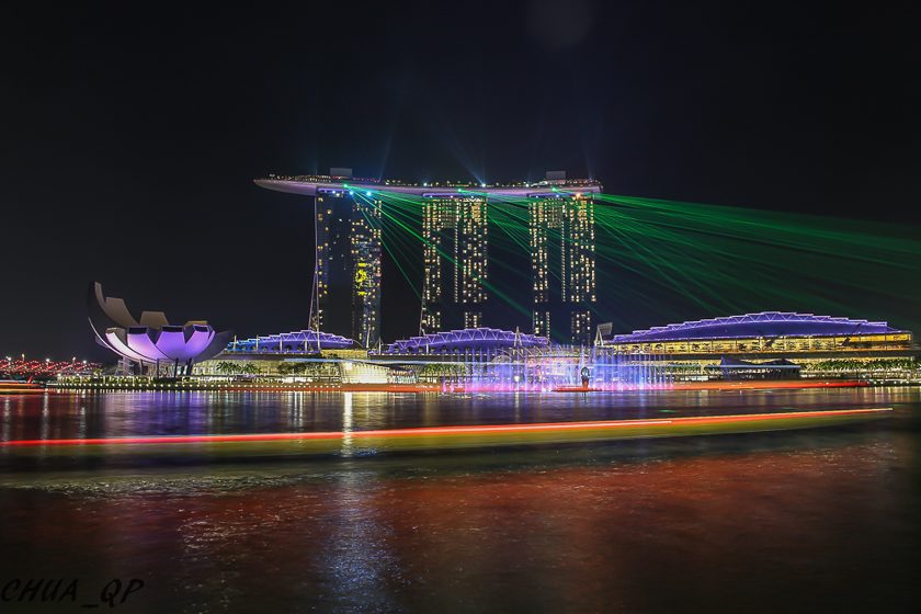 Colourful waterfront lights and a laser display reflected in water